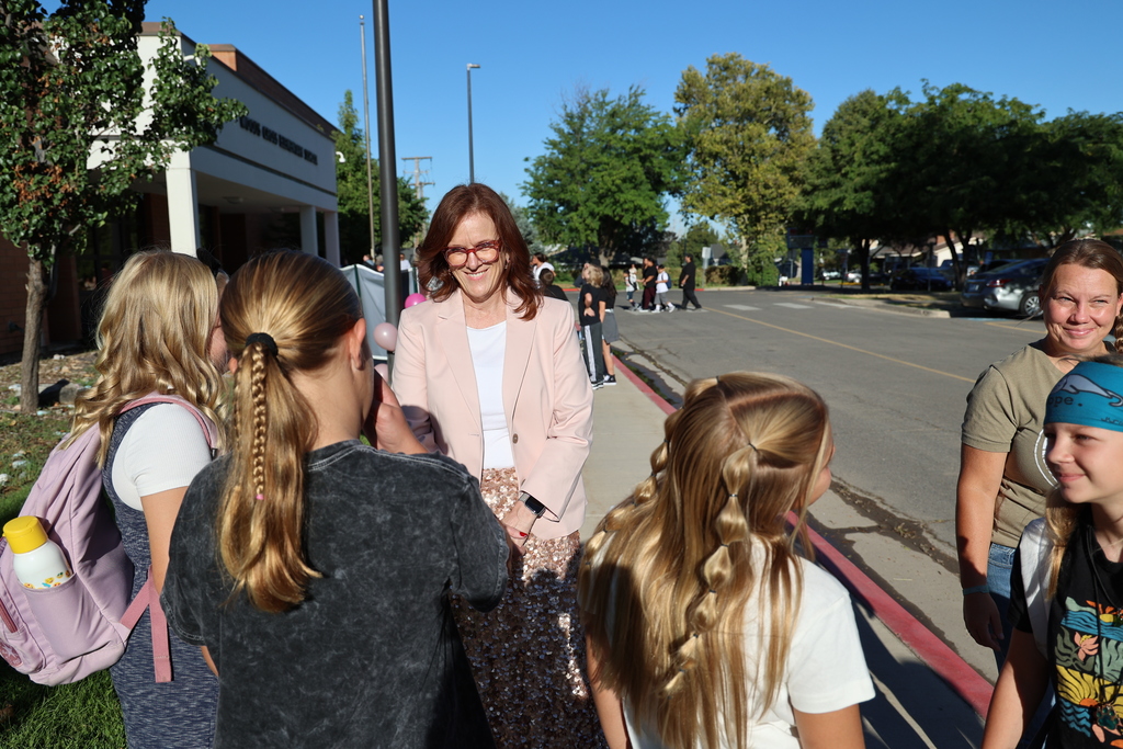 a principal smiles greeting students.