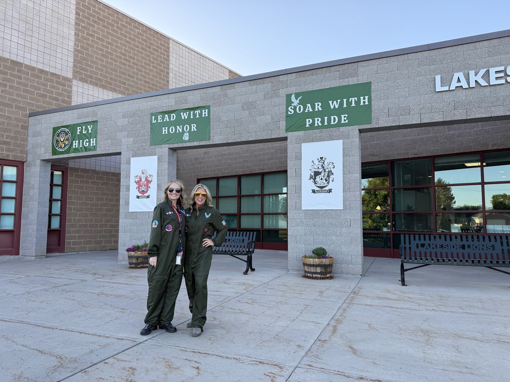 Admin in front of the school with theme: Fly High, Lead with Honor, and Soar with Pride!