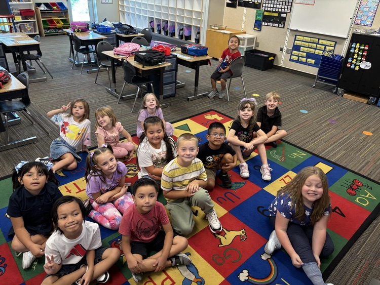 1st graders sitting on a rug smiling