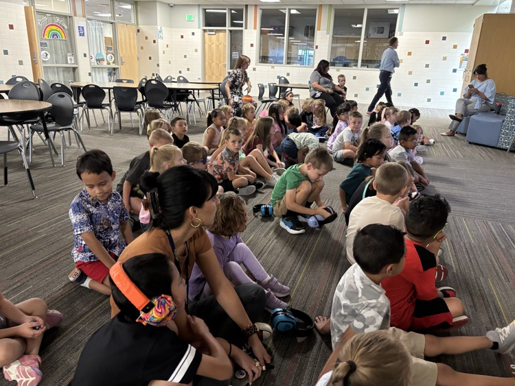 1st graders sitting on the floor looking at the presenter in an assembly