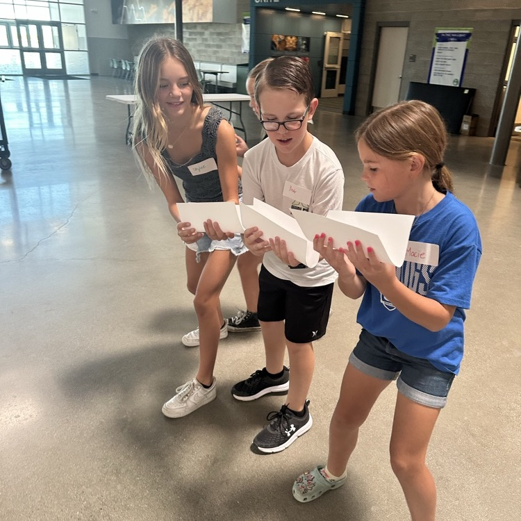 group of students in a line moving ball with paper