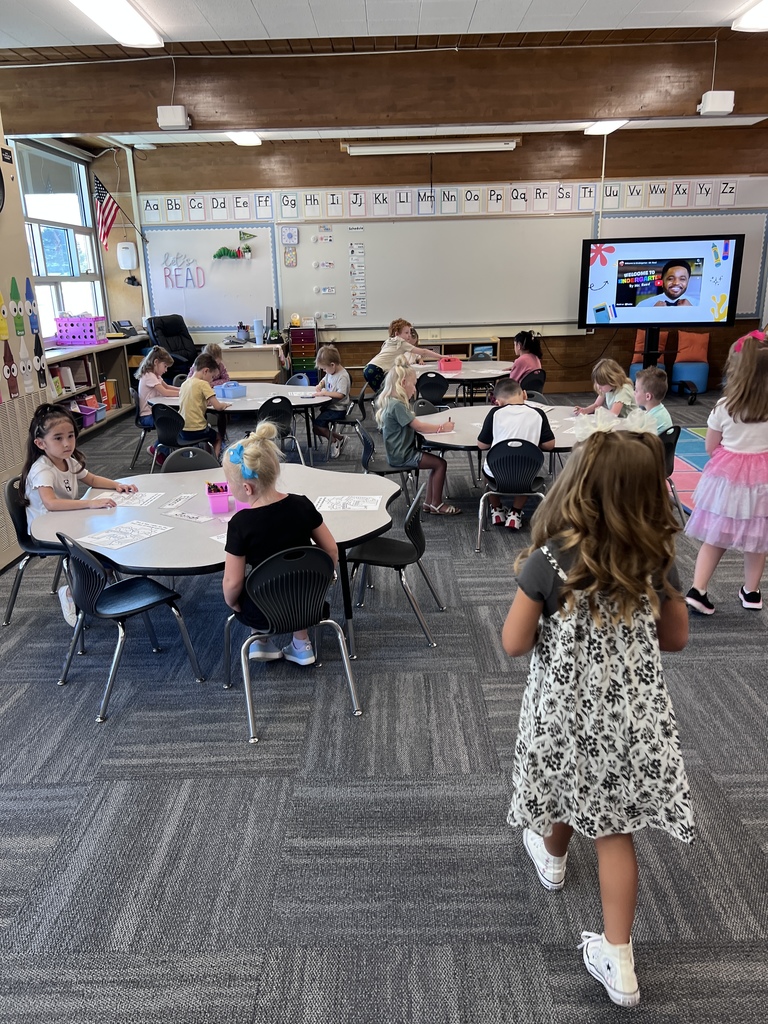 Students walking into their classroom and finding their seats next to some students already seated