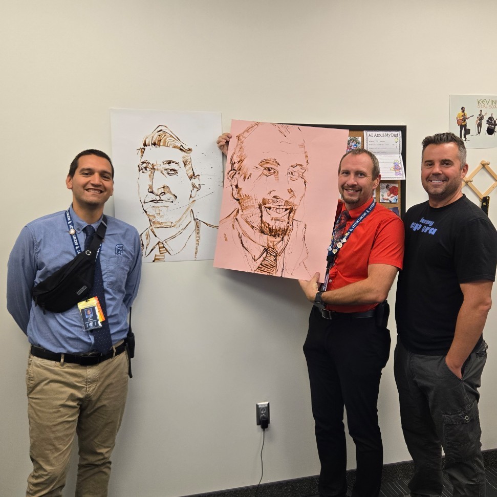 Mr. Castro and Mr. King showing off portraits Mr. Crane painted of them out of chocolate