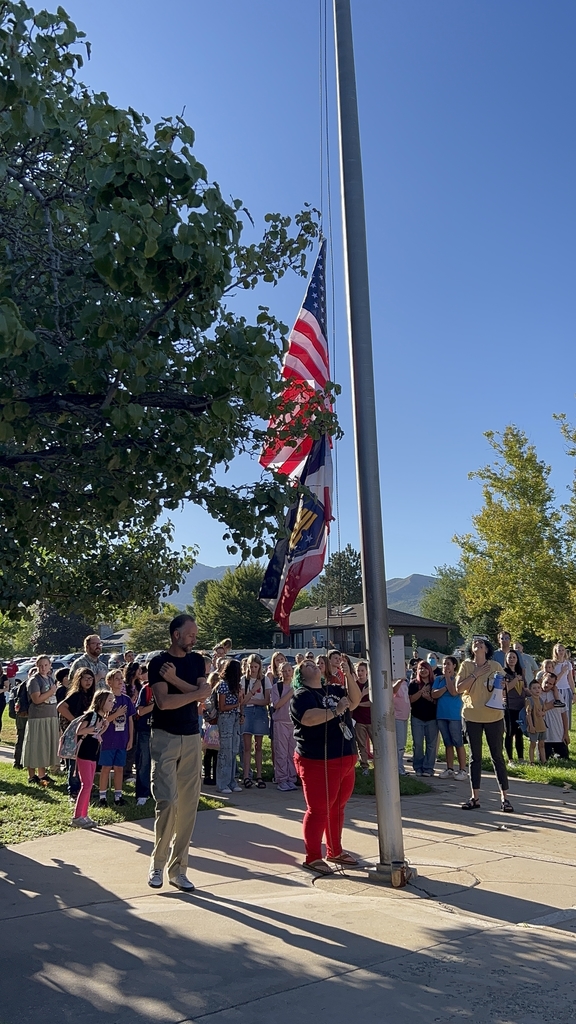 Mrs. Goudy and Mr. Knight Raise the American flag as meadowbrook staff and students place their hands over their hearts