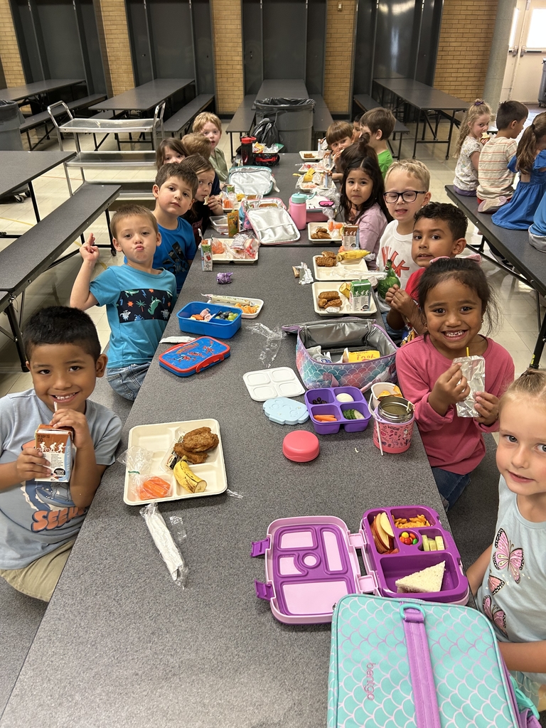smiling students eating home and school lunches in a cafeteria