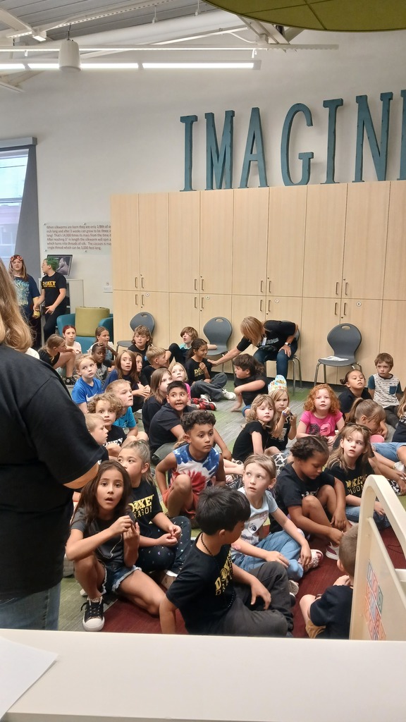 Altruismo house meeting together in the library wearing black t-shirts. Students are sitting and listening to their house leaders