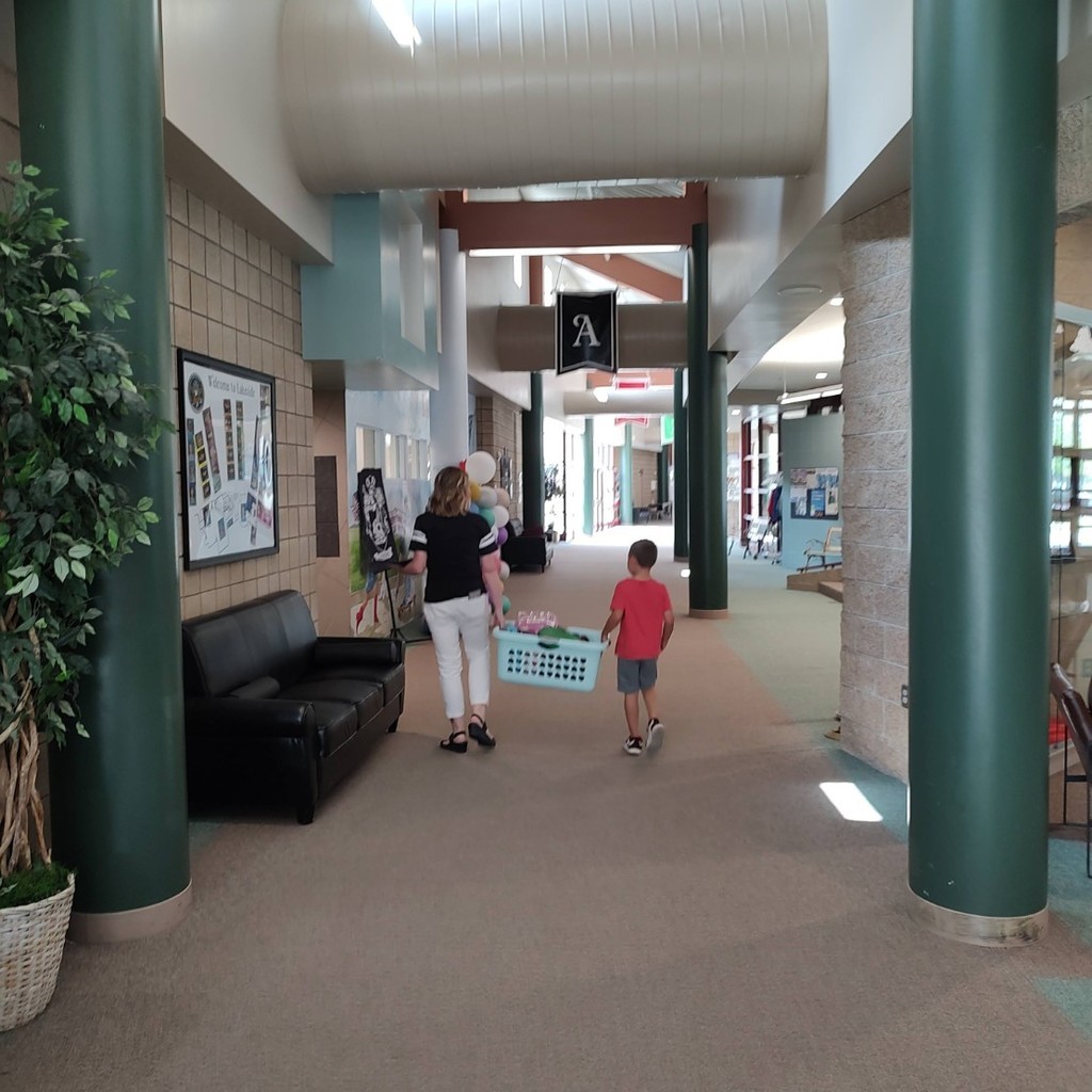 Teacher and student carry lunchboxes down the hall.