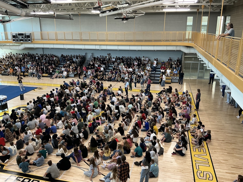 Students sitting on the gym floor.