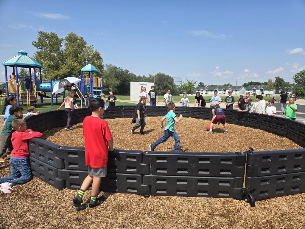 Several students watching a game of Gaga Ball during their lunch recess on  sunny day