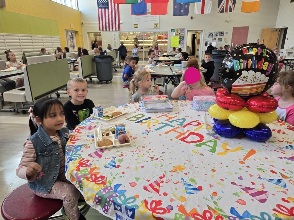 July and August Birthdays kids smiling while sitting at a round table with birthday balloons and a happy birthday table cloth