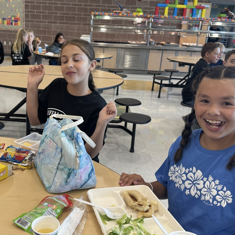 A girl dancing from a seated position in the cafeteria