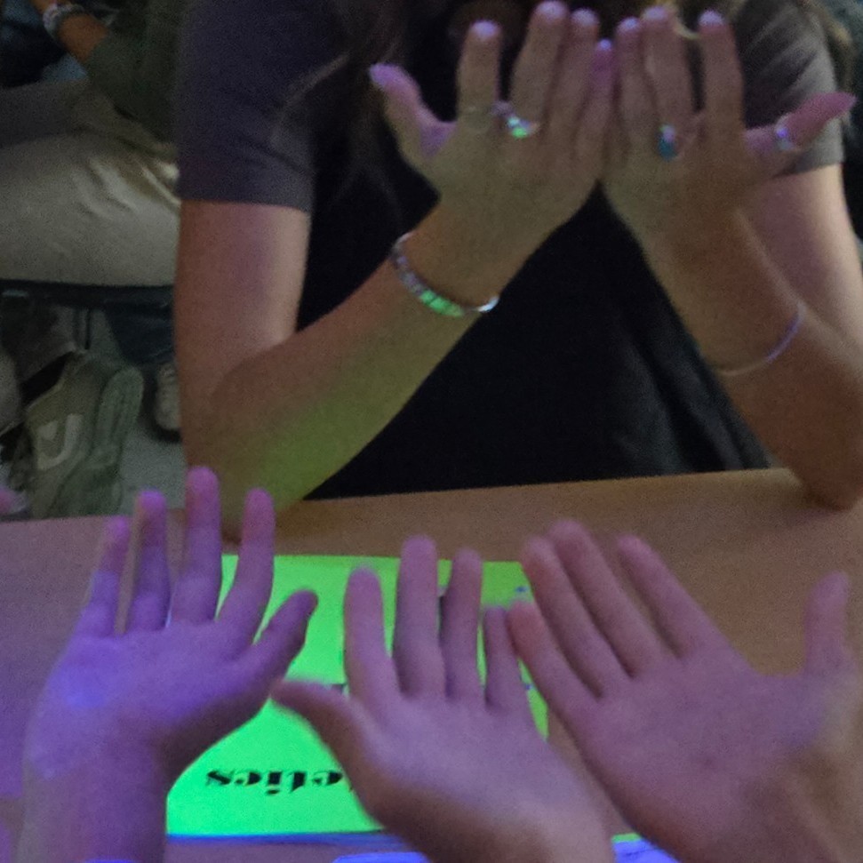 Students looking for germs on their hands under a black light.