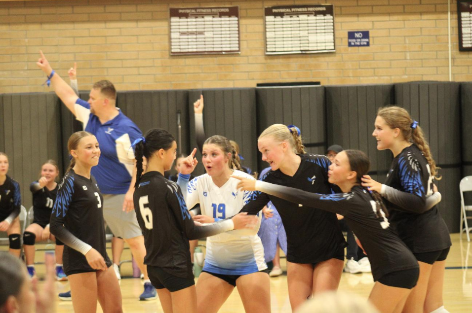 One More Point! All the ladies on the the court are cheering on each other for the last point of the game. Coach Eliason and the rest of the ladies on the bench have one finger held up in the background.