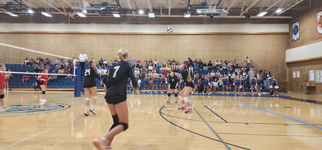 Fairfield's number 25 is passing a ball while three of her team mates are preparing to play the passed ball. In the background is the crowd seated in the bleachers.