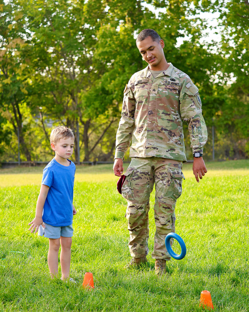 A student throws a ring with the help of a U.S. Army member. 