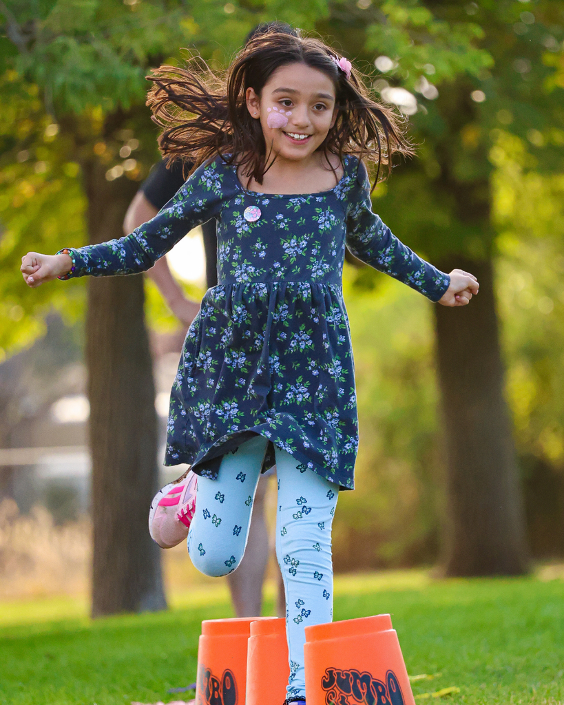 A student smiles mid-jump while jumping over jumbo cones. 