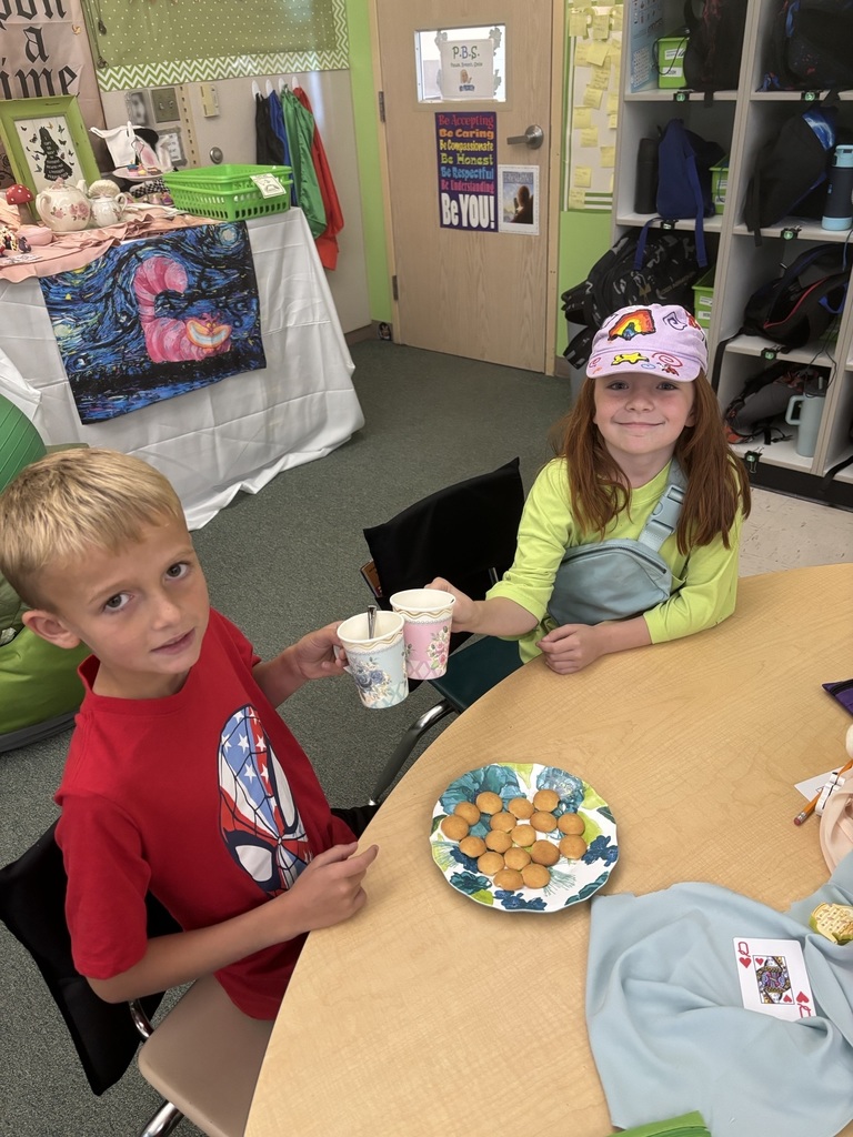 Students holding paper tea cups dressed up for a Mad Hatter Tea Party.