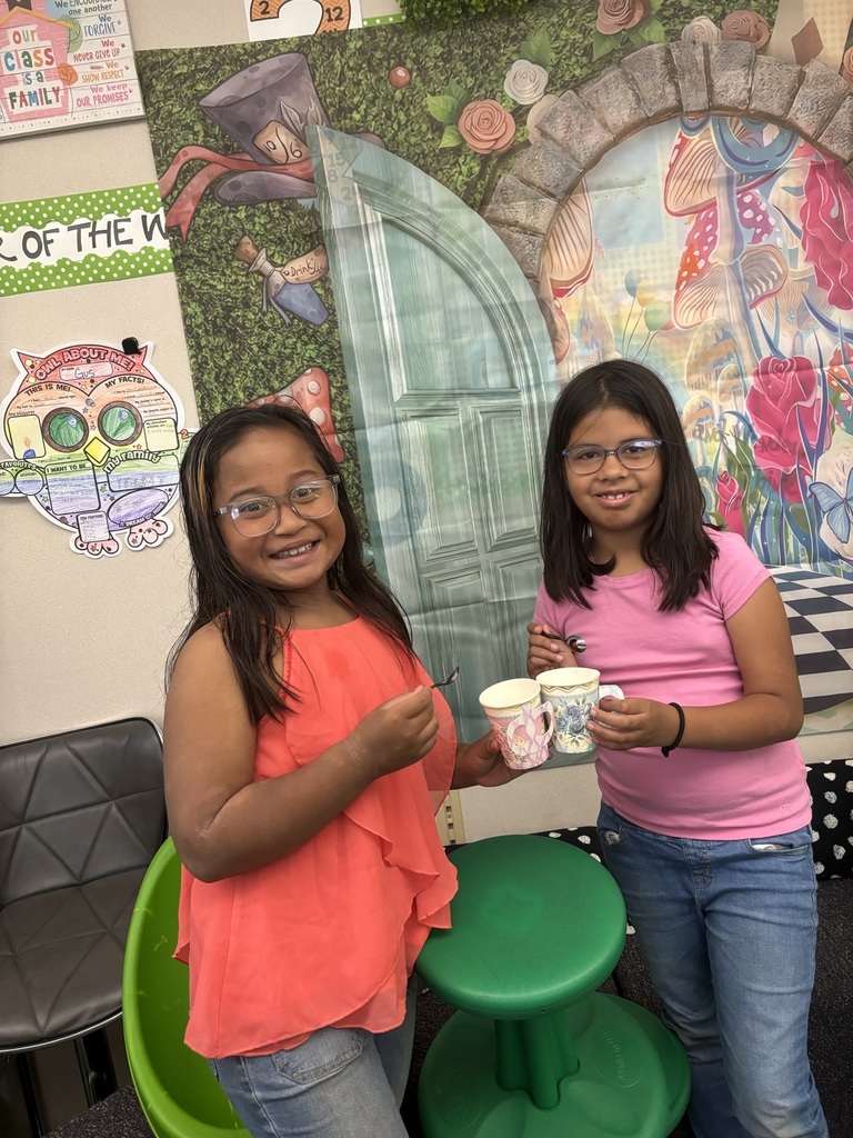 Students holding paper tea cups dressed up for a Mad Hatter Tea Party.