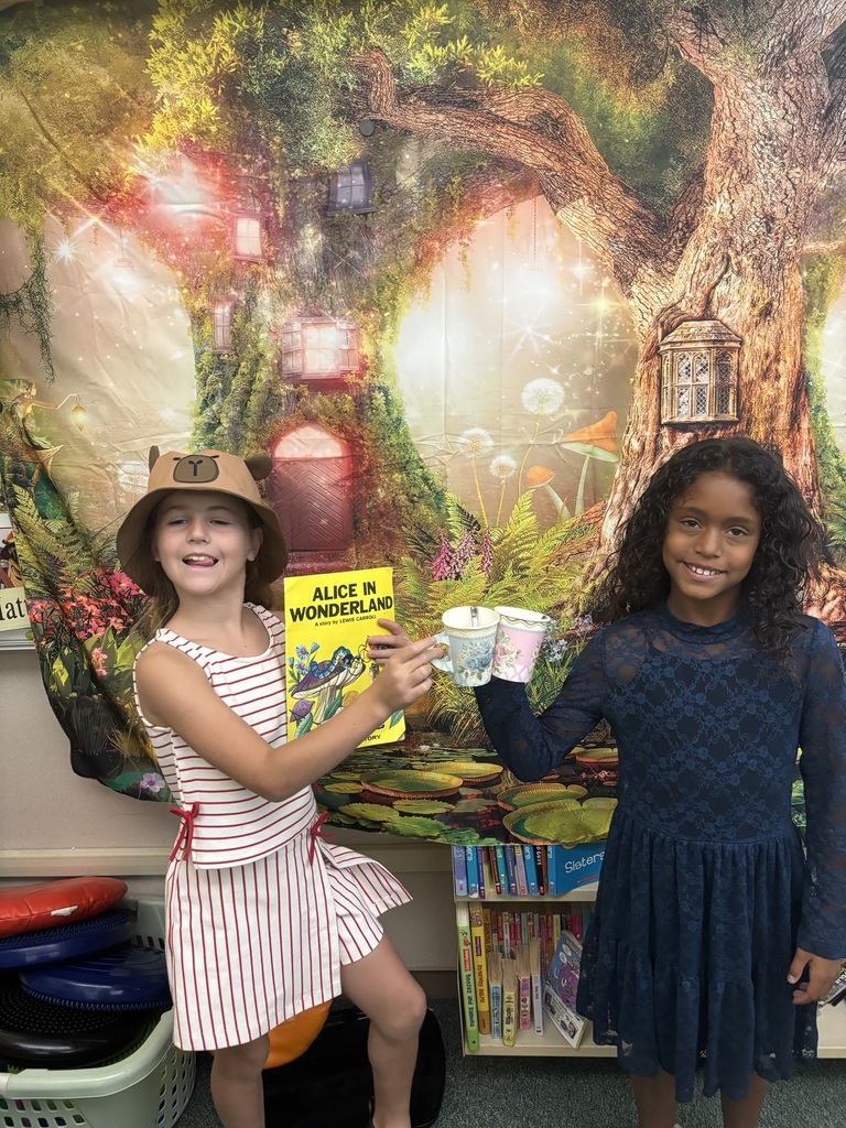 Students holding paper tea cups dressed up for a Mad Hatter Tea Party.