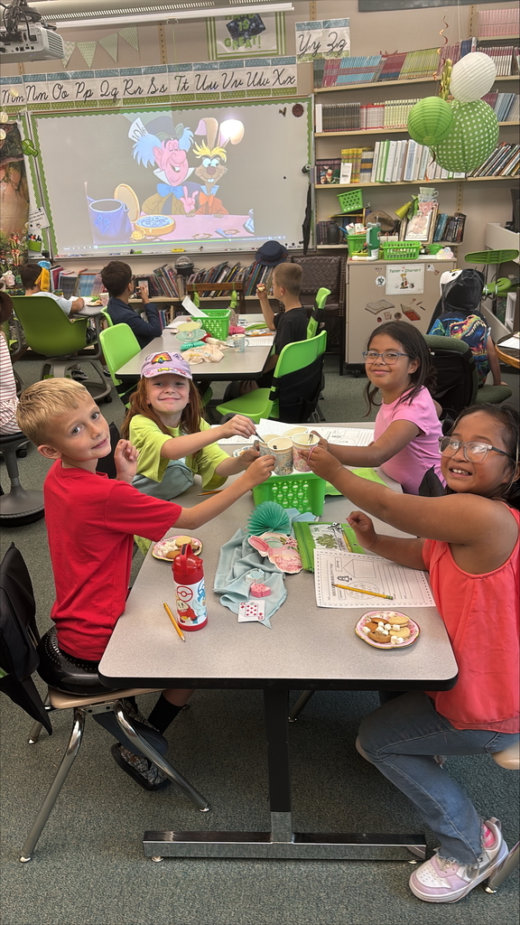Students holding paper tea cups dressed up for a Mad Hatter Tea Party.