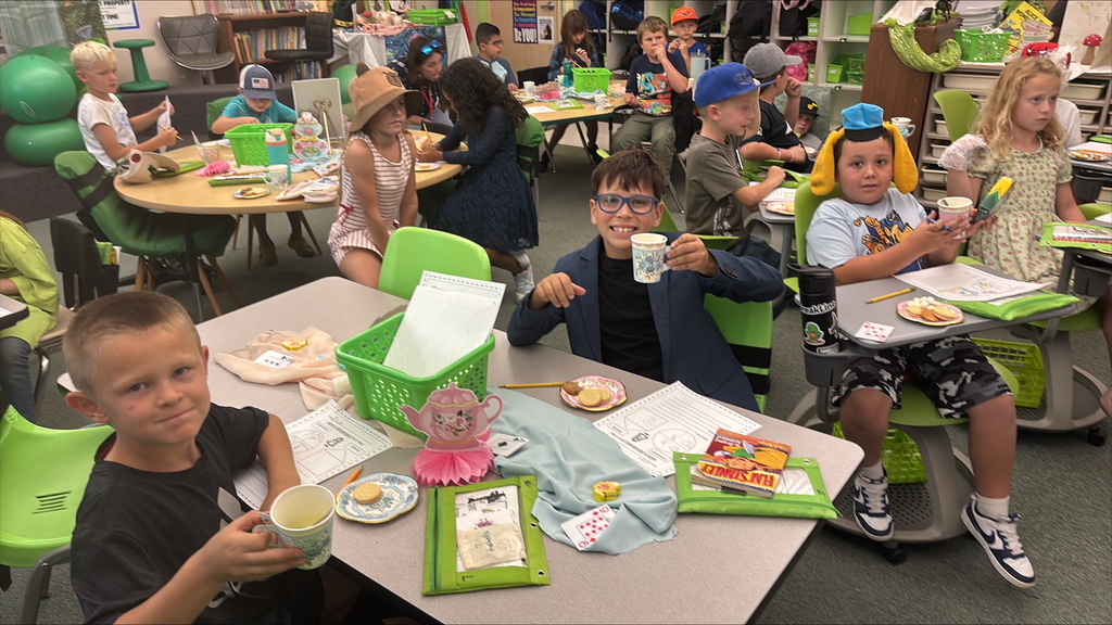 Students holding paper tea cups dressed up for a Mad Hatter Tea Party.