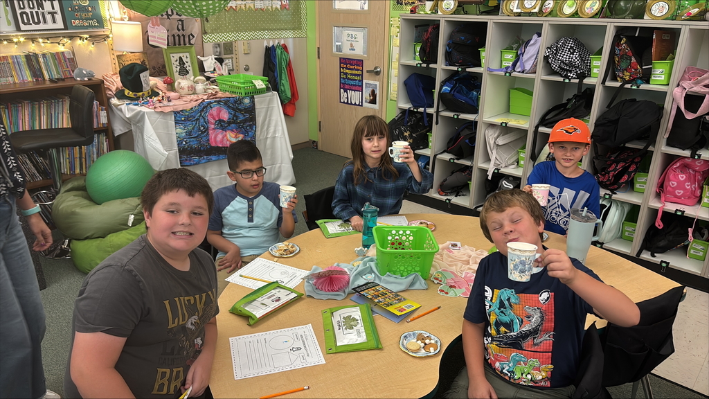 Students holding paper tea cups dressed up for a Mad Hatter Tea Party.