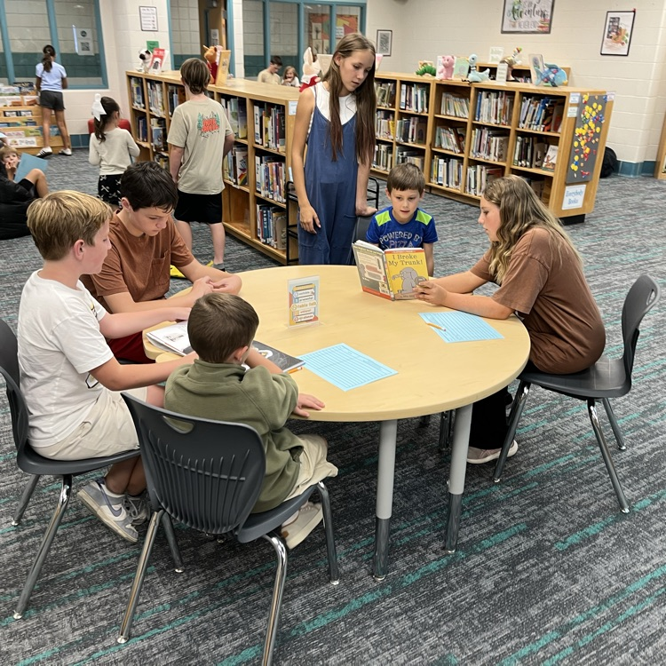 Many students can be seen reading together and smiling in the library.