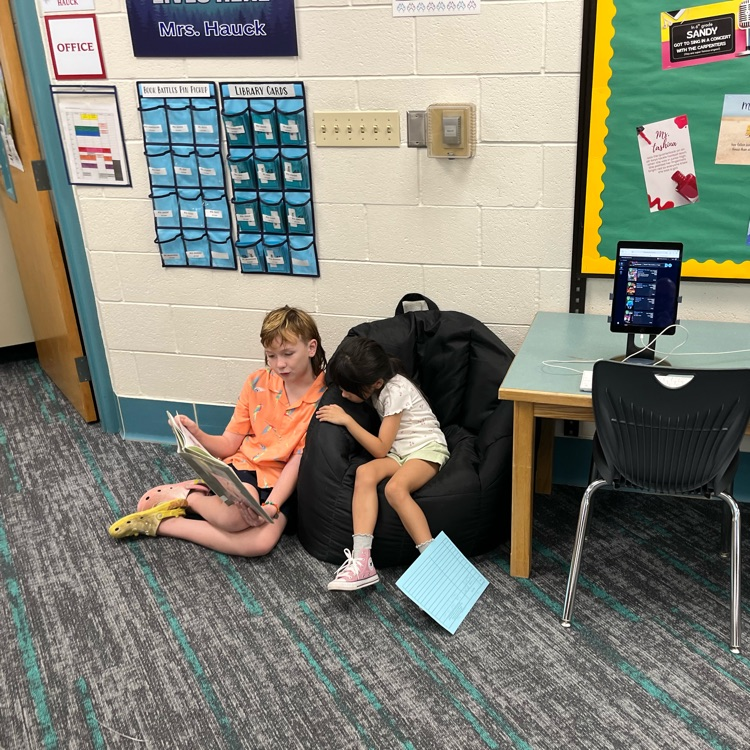 Many students can be seen reading together and smiling in the library.