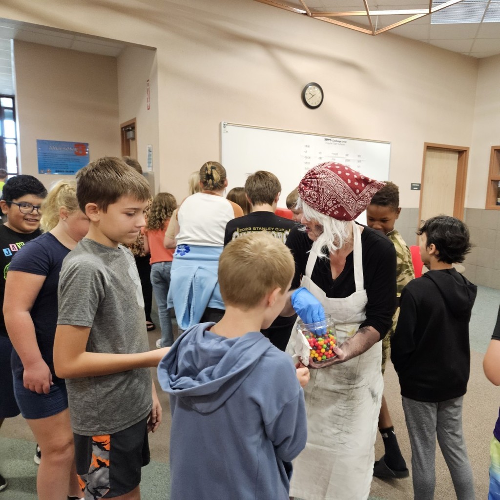 Mrs. Pratchett hand candy out to students.