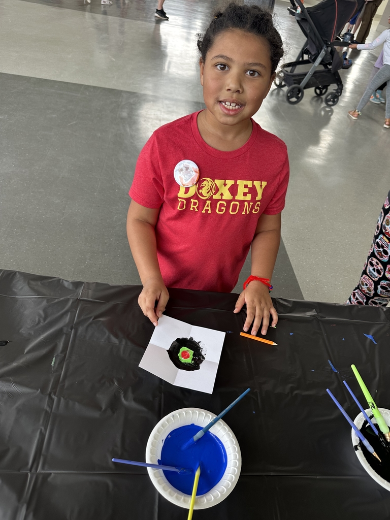 Student posing with their artwork that they created during Doxey's spirit night