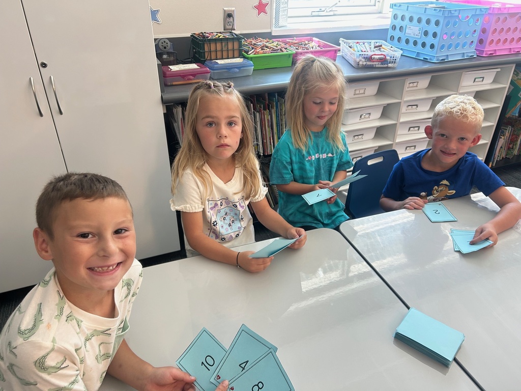 a boy and two girls holding blue cards with numbers on them