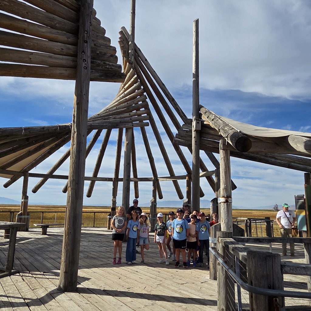 a group of students smiling at the camera while standing on a wooden platform over the wetlands