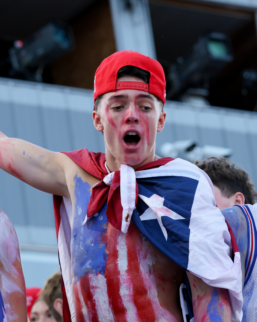 A student wearing an American flag points to the left yelling. 