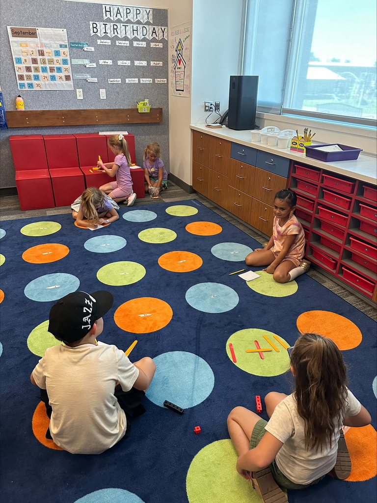 Six students sitting at a rug with math manipulatives