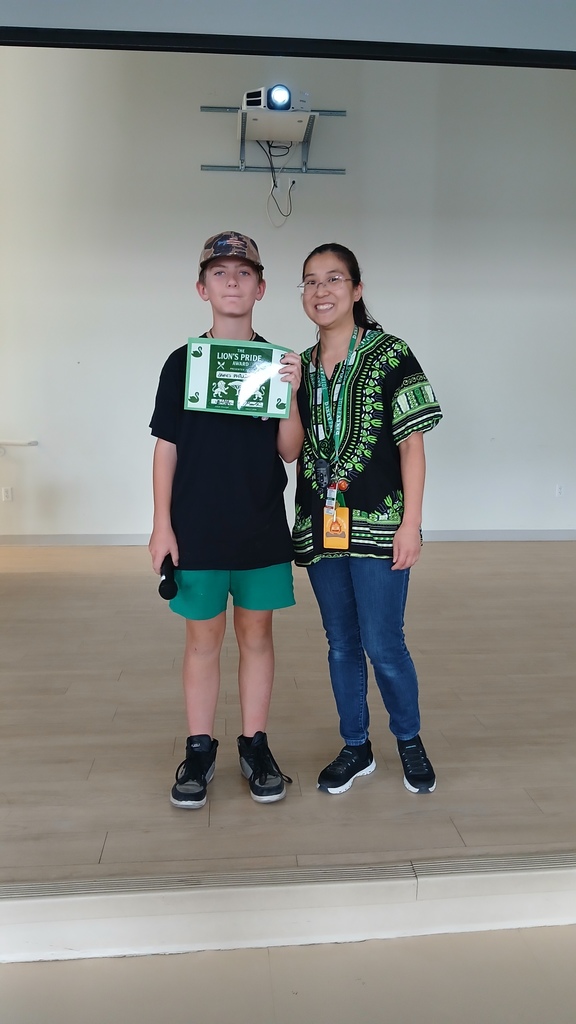 Isibindi house leader Mrs. Martinez posing side by side with James who is wearing a hat and posing with his green certificate.