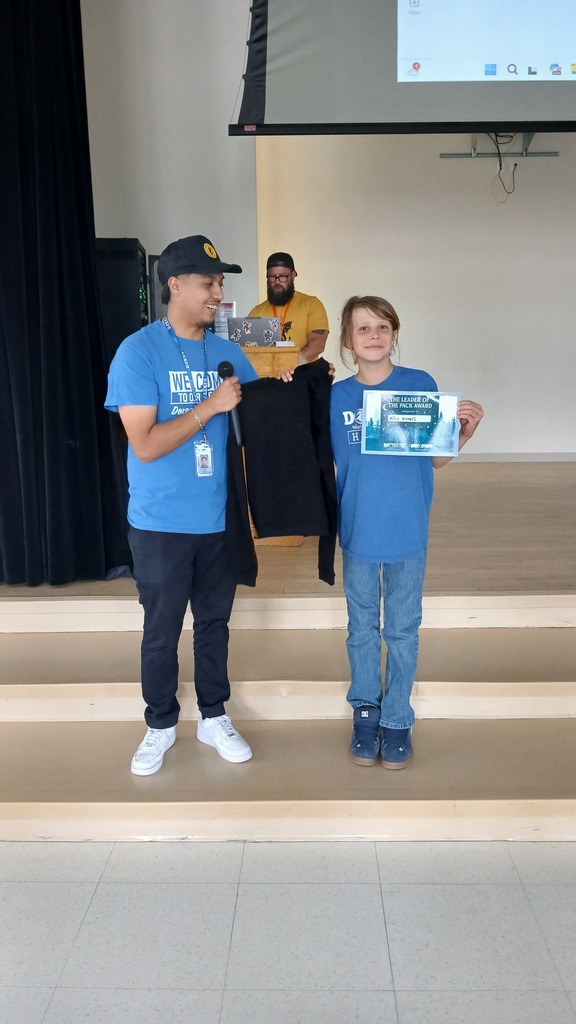 Reveur house leader Mr Escalante is posing side by side with Milo who is holding her blue certificate with one hand and a new black long sleeve shirt with her other hand