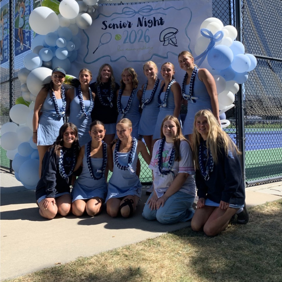 girls tennis players in front of a senior night sign and balloons
