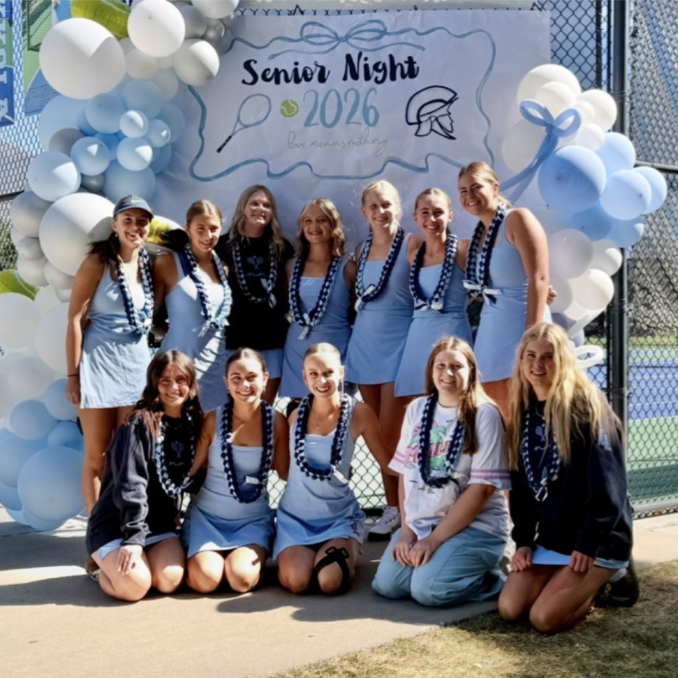 girla tennis players in front of a senior night sign and balloons