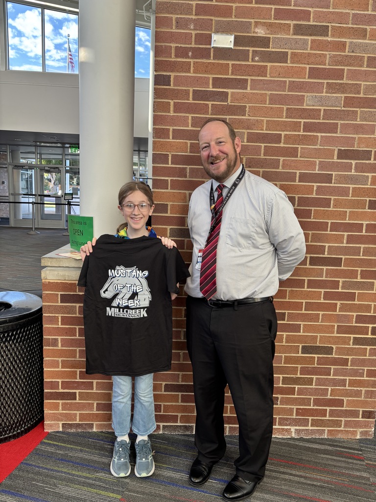 An image of our Mustang of the Week and our school principal. The student is holding up a shirt that says "Student of the Week" with our Millcreek Mustangs logo