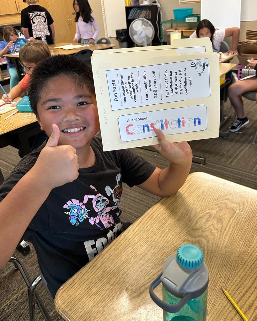 A student holding up a Constitution folder and giving a thumbs up. 