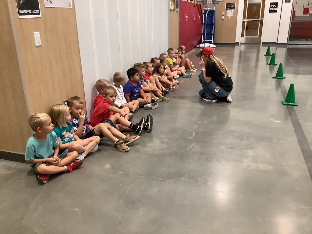 Students sitting against a wall listening to a teachers directions