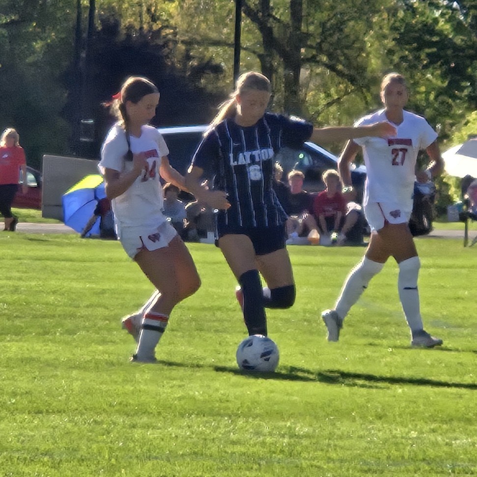 Layton soccer player dribbling between two defenders