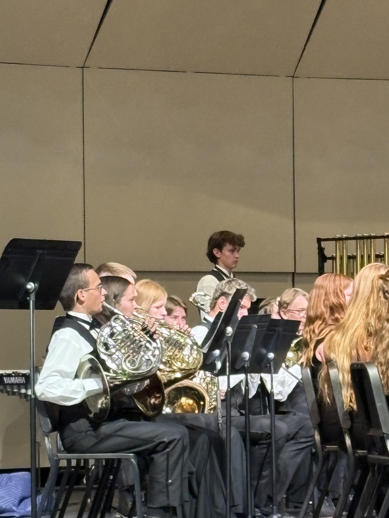 An image of the Millcreek Jr High  bad being conducted by Mr. Frohm. The students are in dress clothes. dresses and vests and ties. 