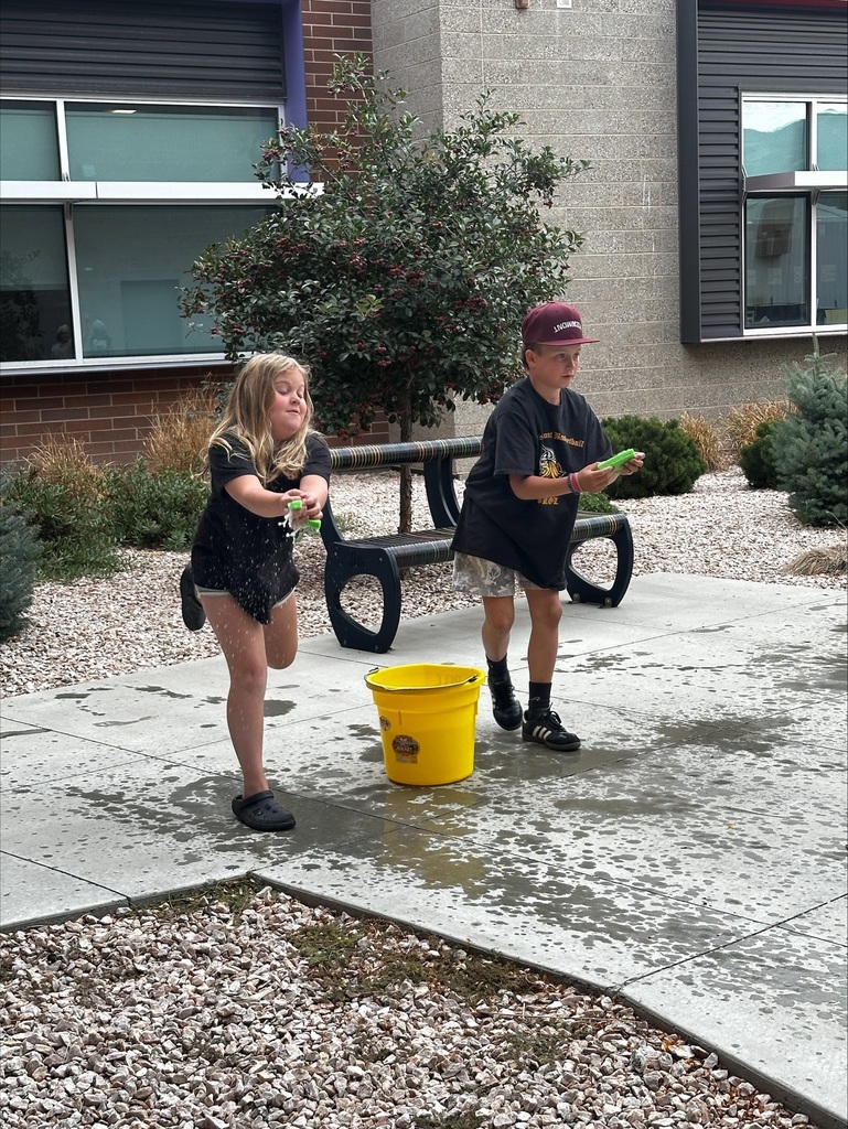 Two students holding sponges next to a water bucket