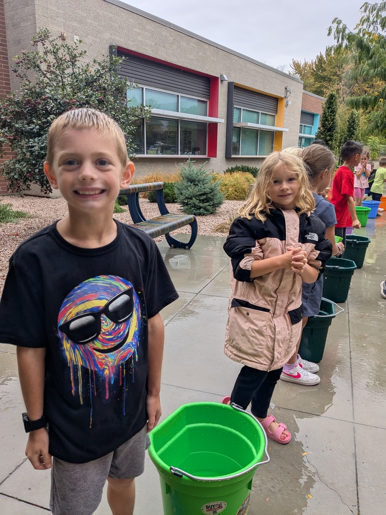 Two students standing next to a water bucket