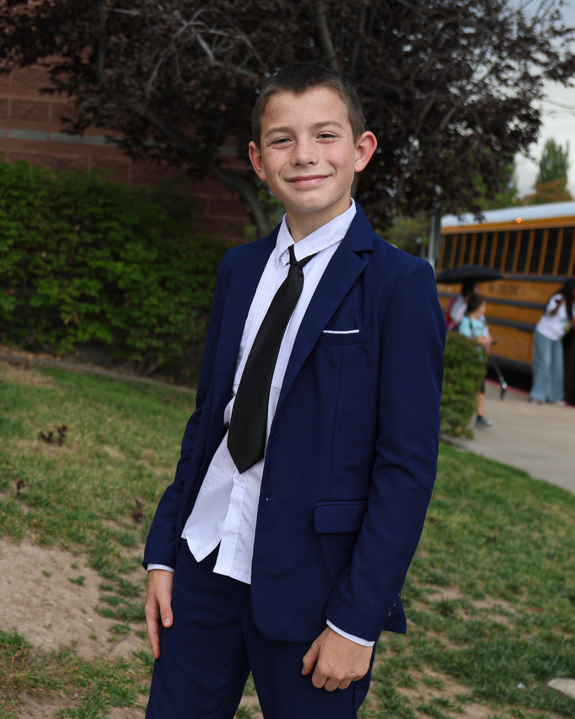 A student in a suit smiles at the camera.