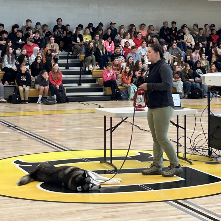Sled dog and owner talking to students