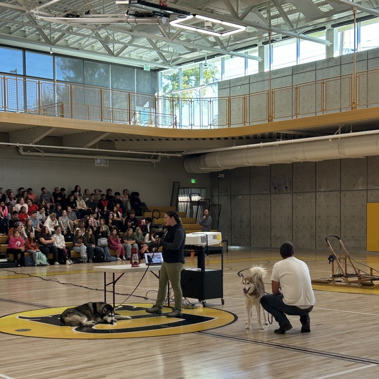 People showing sled and dogs to students with a slide show in the background