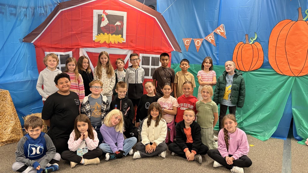 group of students smiling in front of a barn yard and pumpkin background