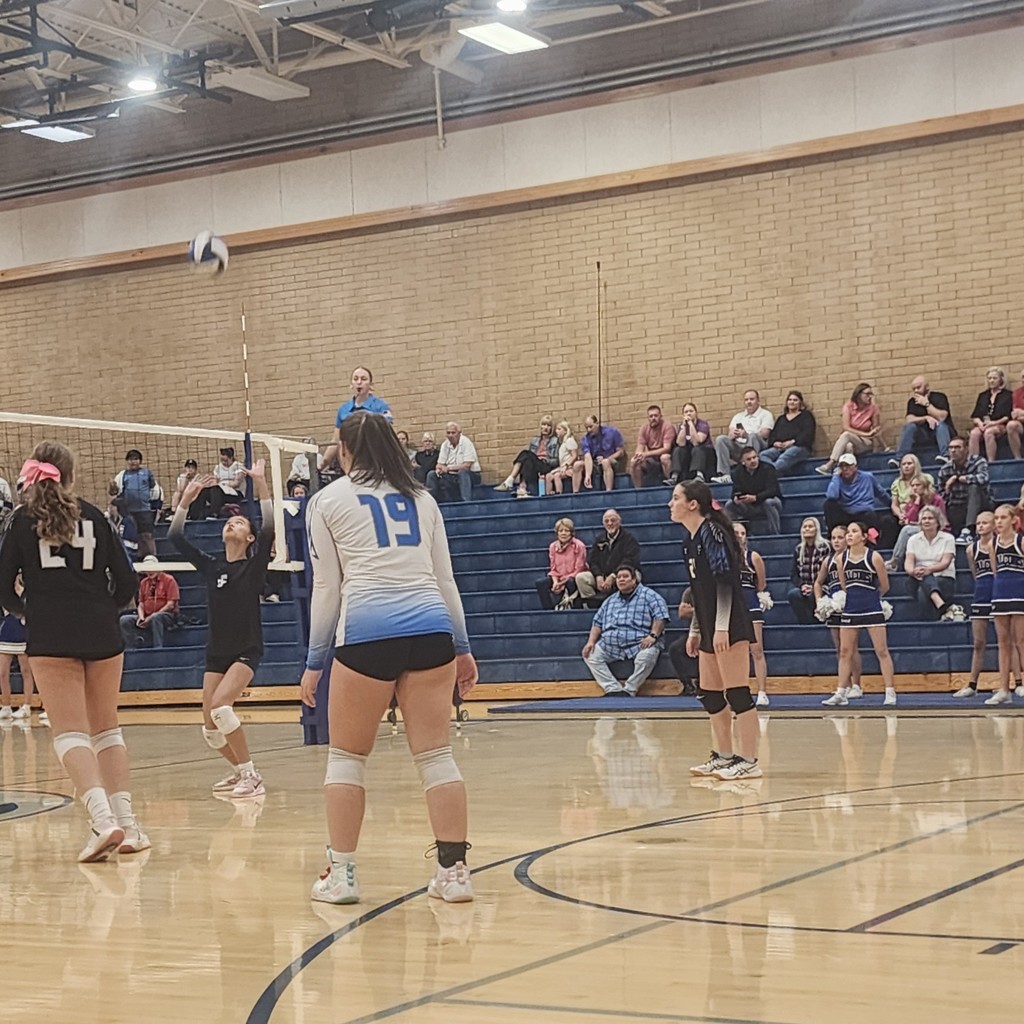 Fairfield watches as the Setter is preparing to set the ball.  The crowd is in the background seated in the bleachers.